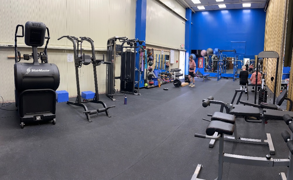 Large weight room with many pieces of equipment, nicely organized for use.